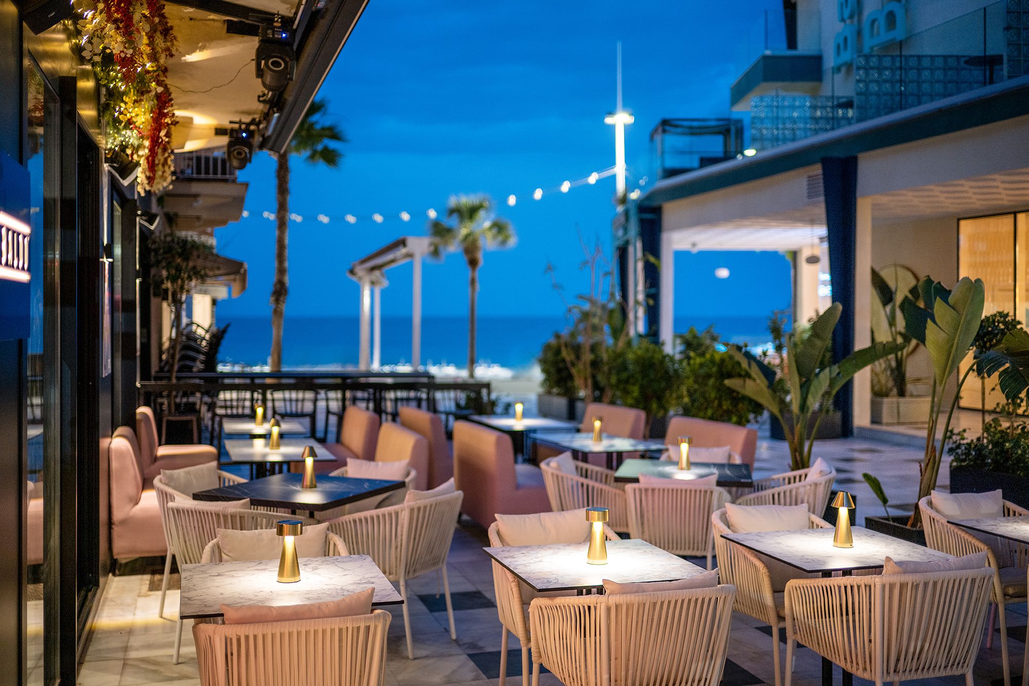 Outdoor dining area on Benidorm beach featuring tables and chairs, with a view of the ocean.
