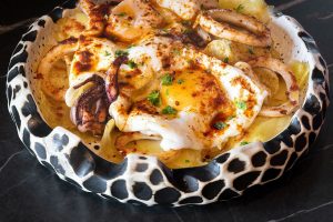 A steaming bowl of mixed food, elegantly topped with a runny egg, creating a delightful and satisfying dish.