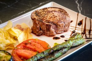 A gourmet plate with a succulent steak, fresh asparagus spears, and fluffy roasted potatoes.