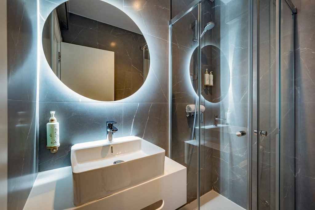 A bright bathroom with a round mirror and a sleek sink, showcasing a simple and elegant style.