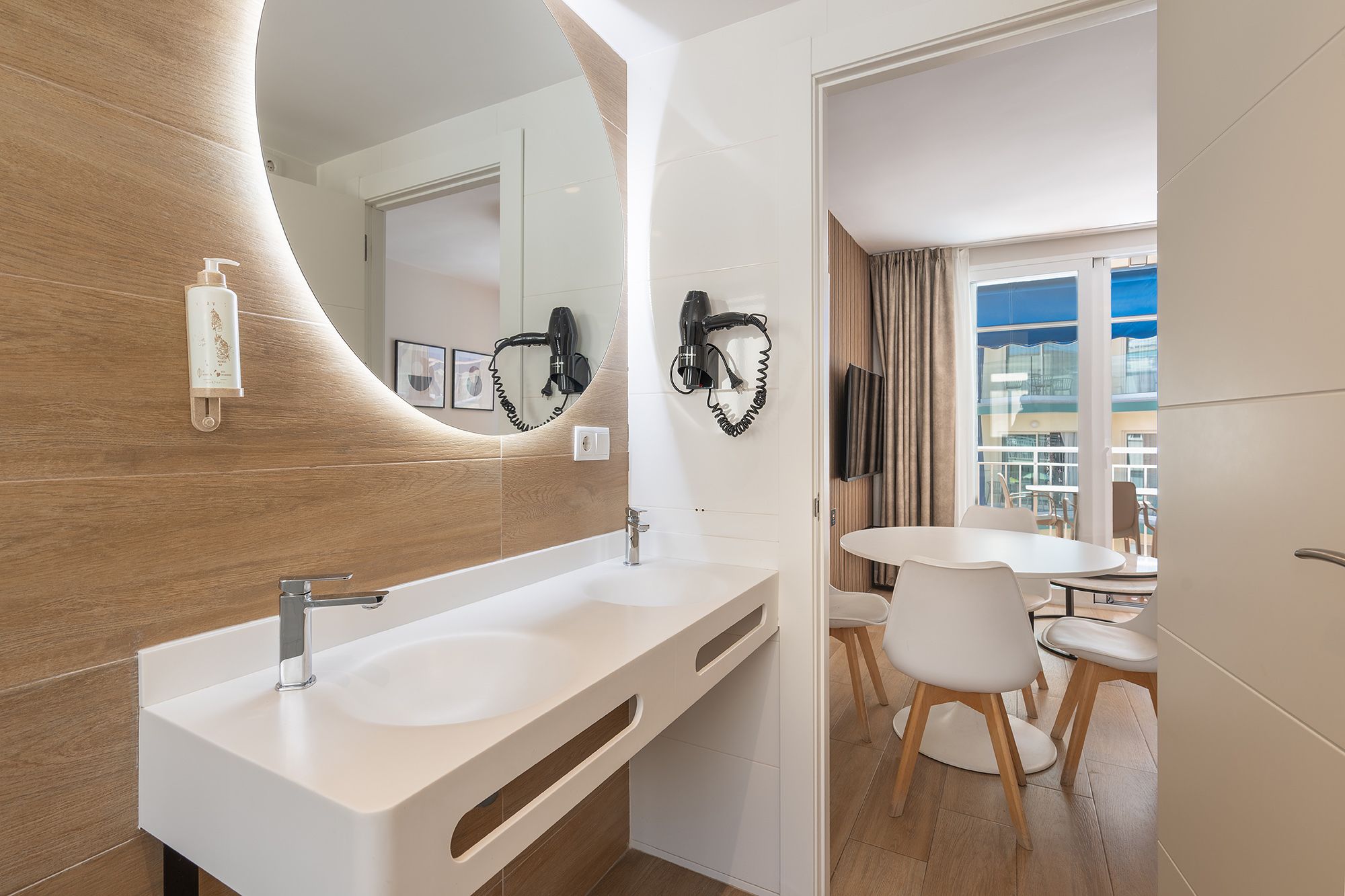 A modern bathroom showcasing a sink, mirror, and a hairdryer ready for use on the vanity.