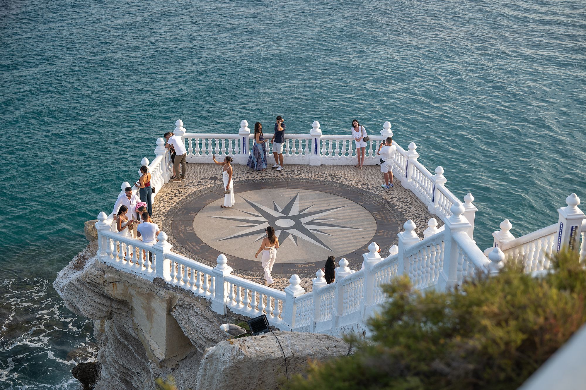 Tourist contemplating views on a cliff overlooking the ocean, with beautiful Benidorm scenery in the background.