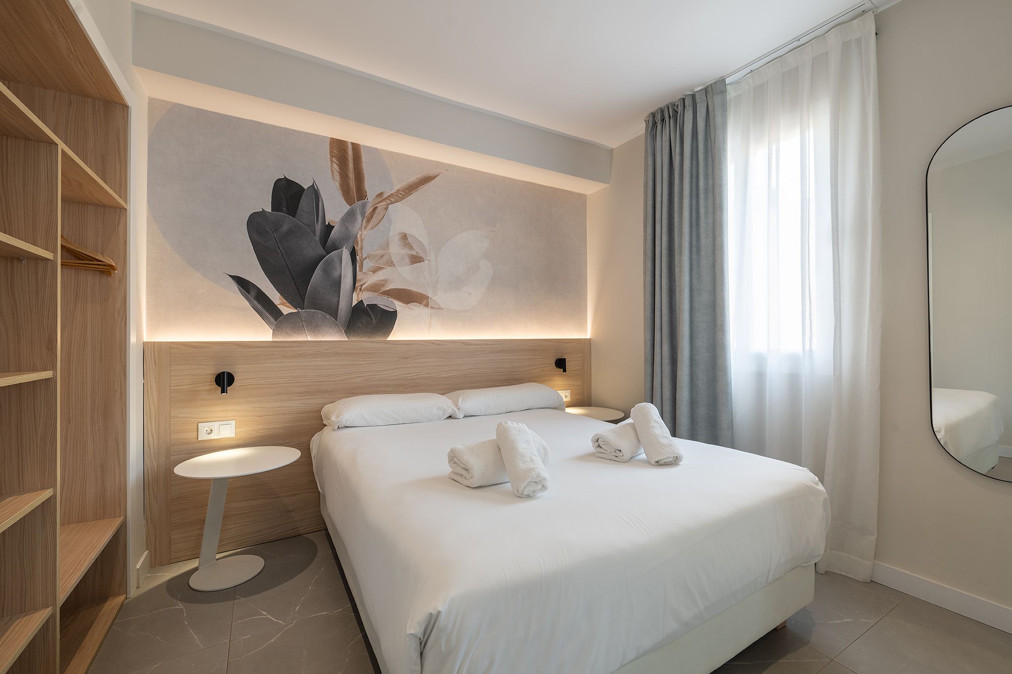 A well-decorated apartment room showcasing a bed and a vibrant wall painting.