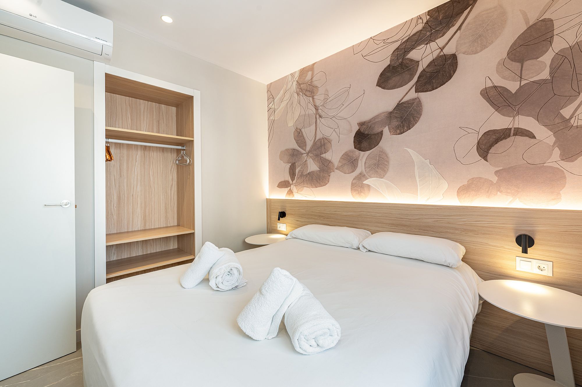 A charming aparthotel room featuring a comfortable double bed and a decorative wall mural that adds a personal touch with minimalistic style