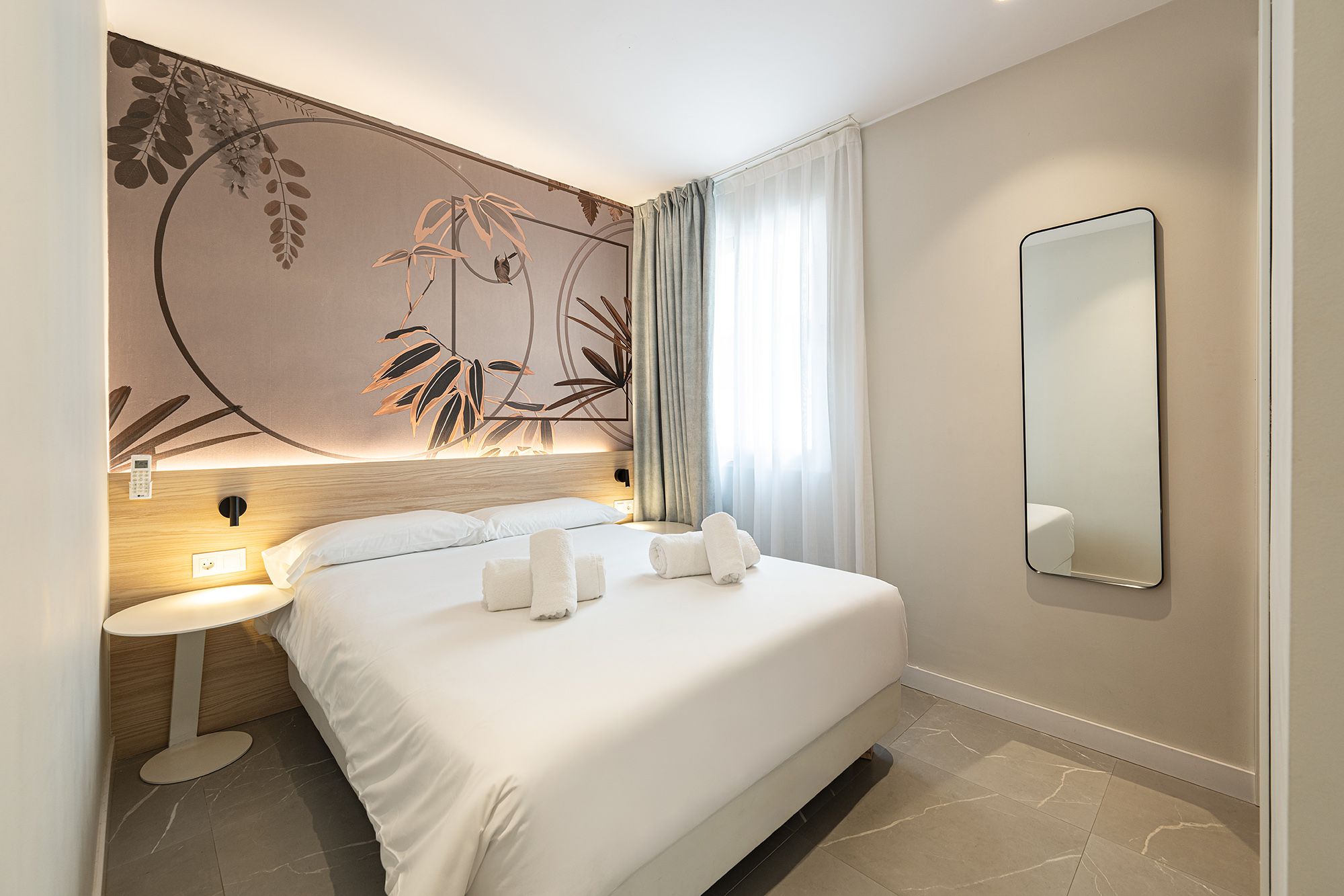 A modern aparthotel room with a soft bed and an eye-catching wall mural, creating a unique and inviting environment.