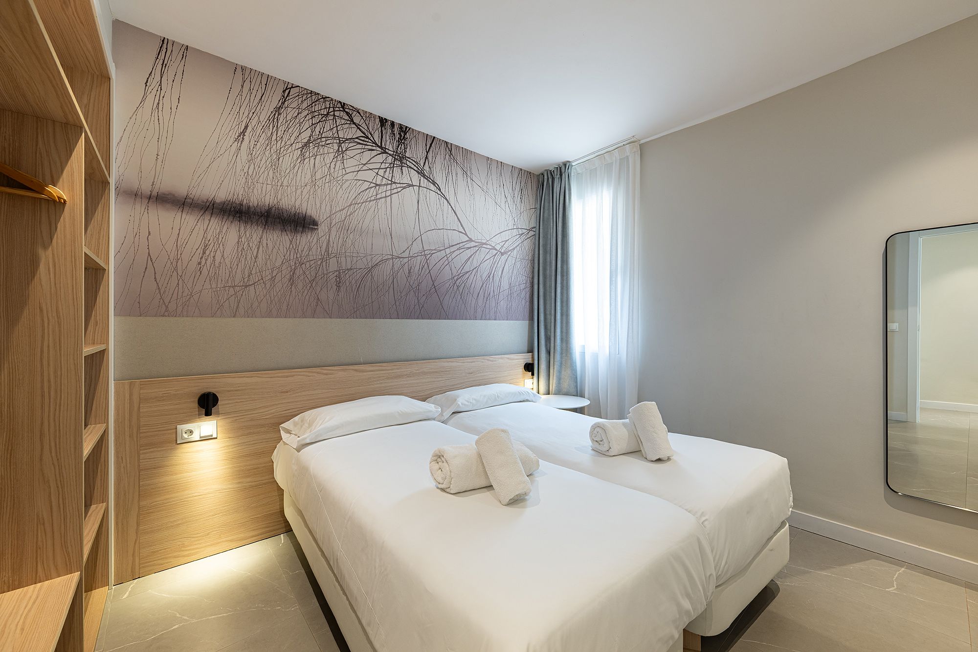 A spacious bedroom showcasing two beds and a vibrant wall painting, perfect for a comfortable stay at Benidorm
