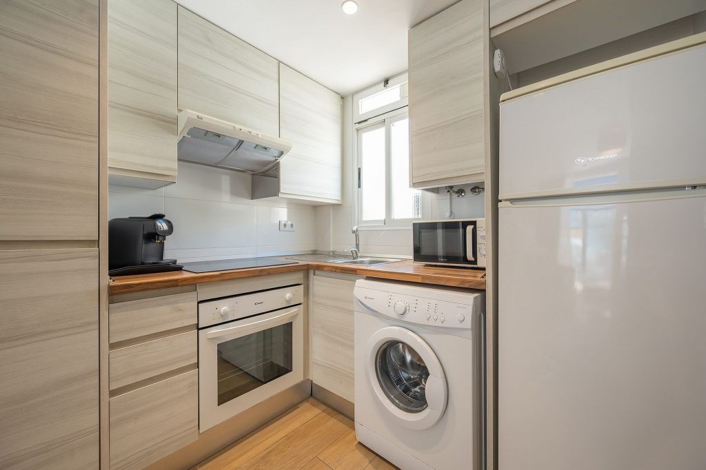 Una cocina compacta con lavadora y secadora apiladas, que muestra un uso eficiente del espacio y electrodomésticos modernos.