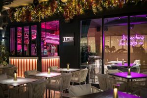 Baldo Restaurant and Bar exterior with beachside tables and chairs, offering a scenic view of the sea.