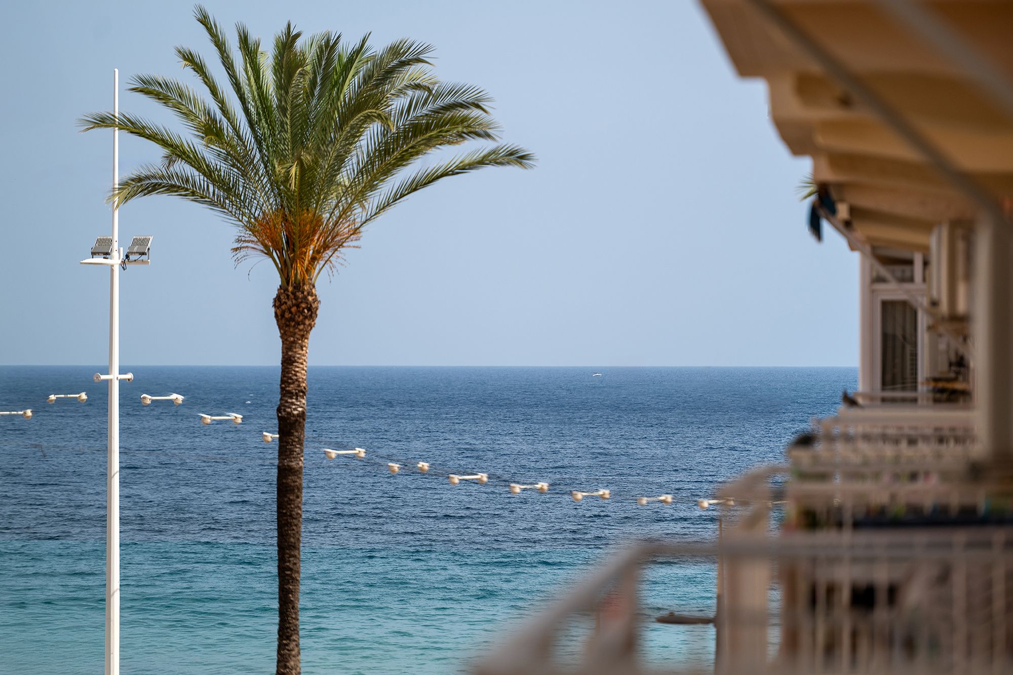 Ocean view from a balcony overlooking Benidorm beach, featuring sandy shores and gentle waves.