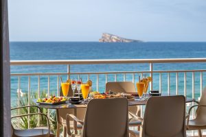 A table laden with breakfast delights, perfectly positioned to overlook the sparkling ocean waves at Mara Boutique Apartments
