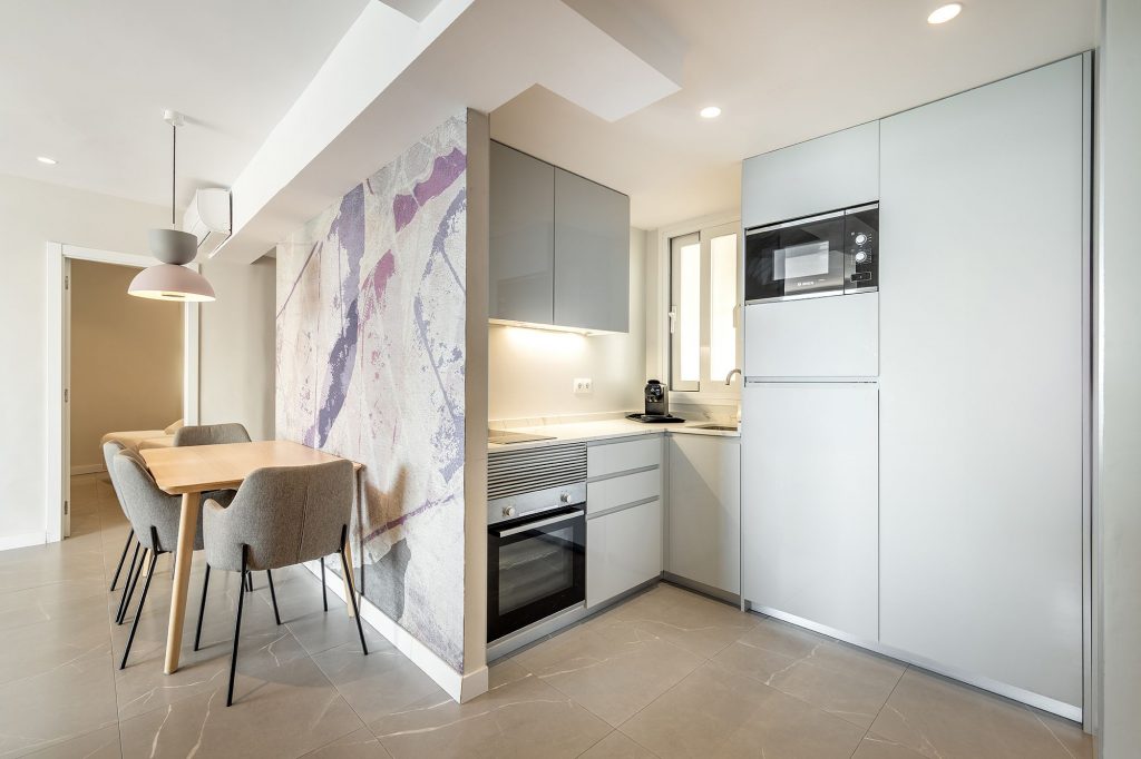 Una cocina moderna con una mesa con sillas, lista para comer.