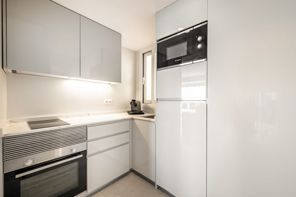 Una acogedora cocina con microondas, frigorífico y otros utensilios.