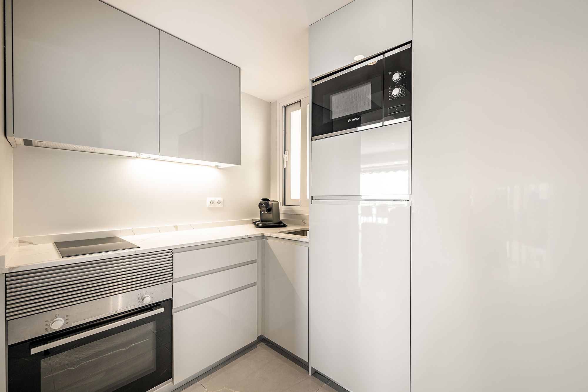 Una acogedora cocina con microondas, frigorífico y otros utensilios.