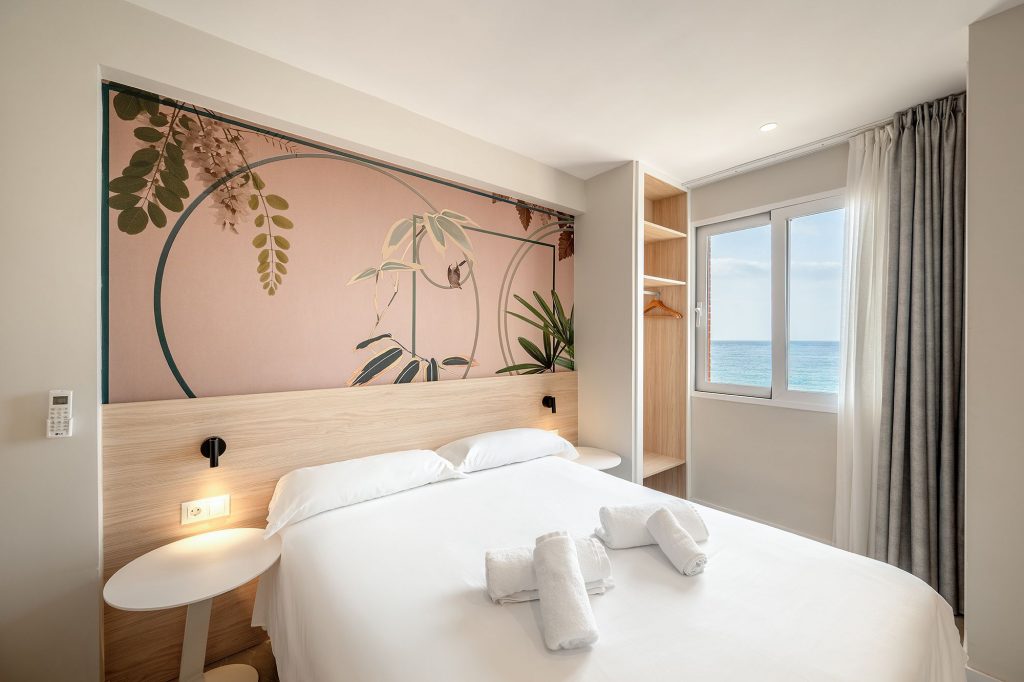 Elegante habitación de apartahotel en el apartamento boutique Mara, con una cómoda cama y un artístico mural en la pared.