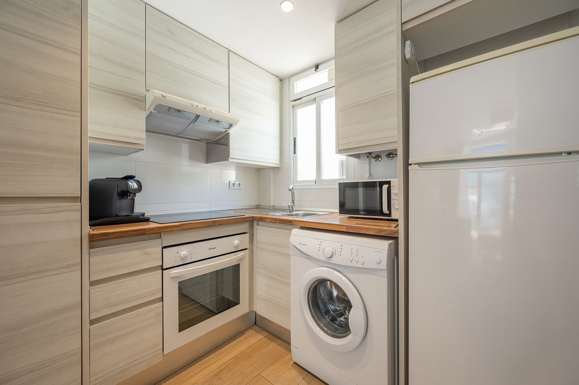 Una cocina compacta con lavadora y secadora apiladas, que muestra un uso eficiente del espacio y electrodomésticos modernos.