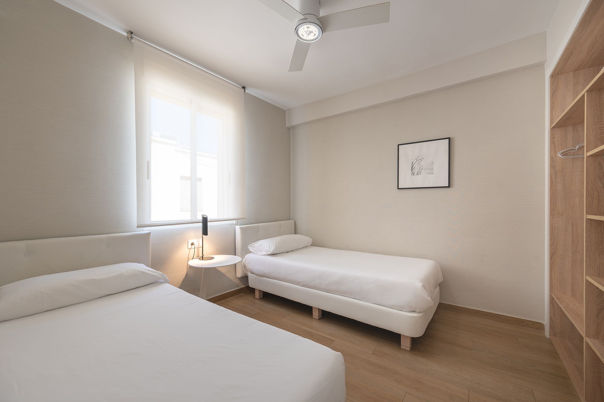 Dos camas individuales en una acogedora habitación con ventilador de techo, que crea un ambiente cómodo y acogedor.