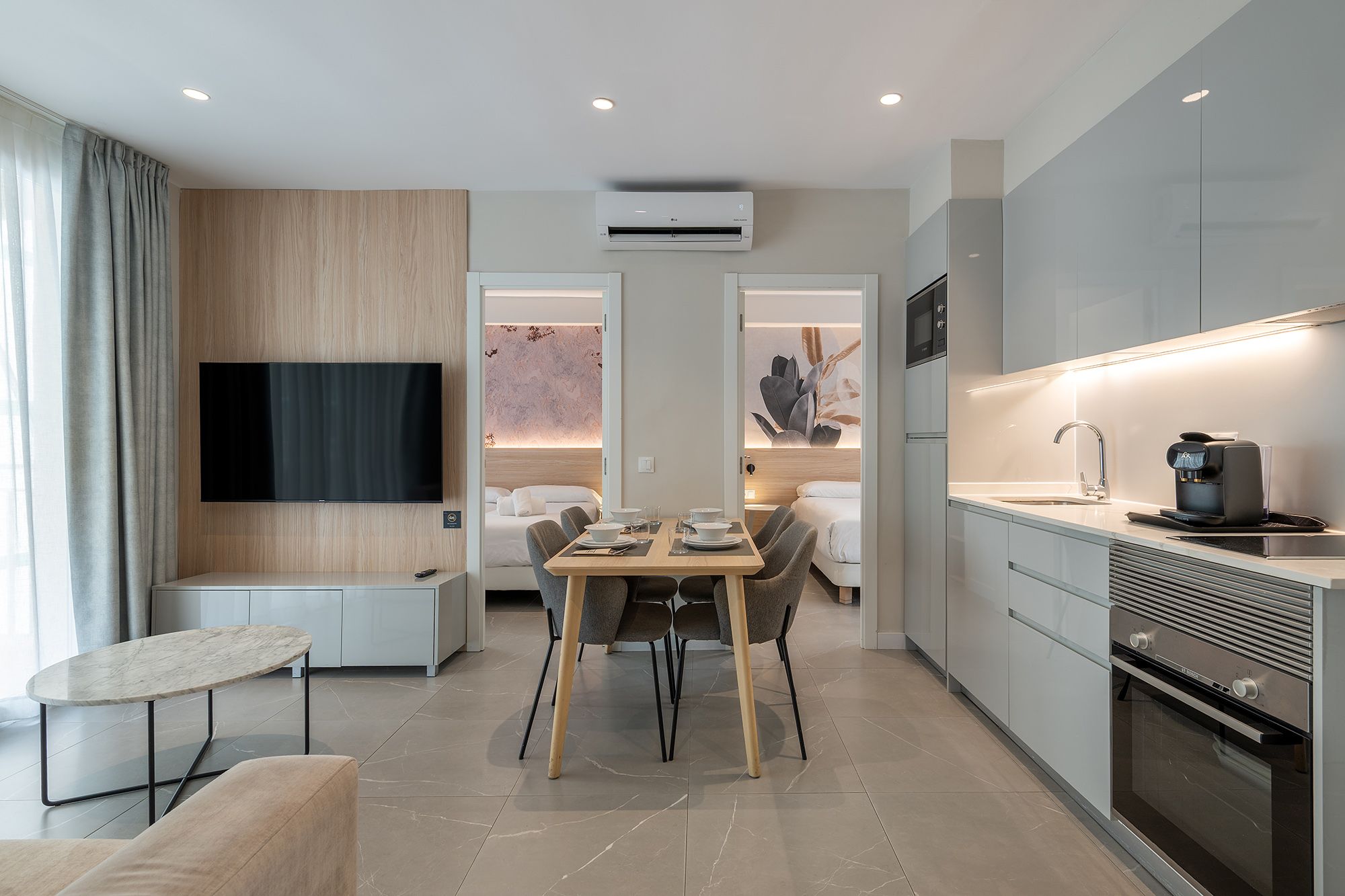 Contemporary apartment showcasing a kitchen, dining area, two bedrooms, smart TV, and air conditioning.