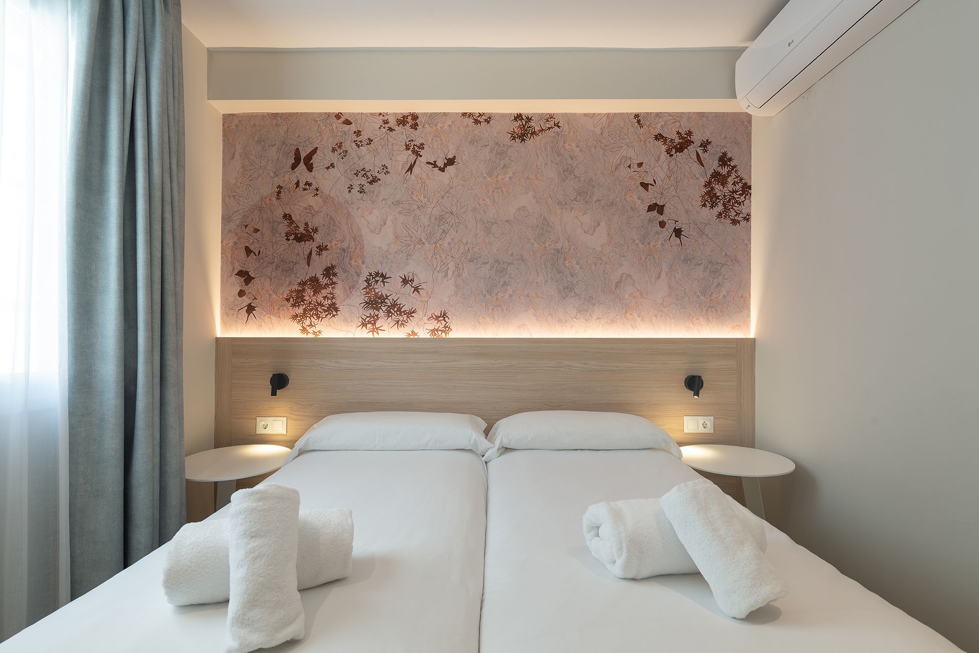 Cozy bedroom featuring a white bed, wall mural and bright window