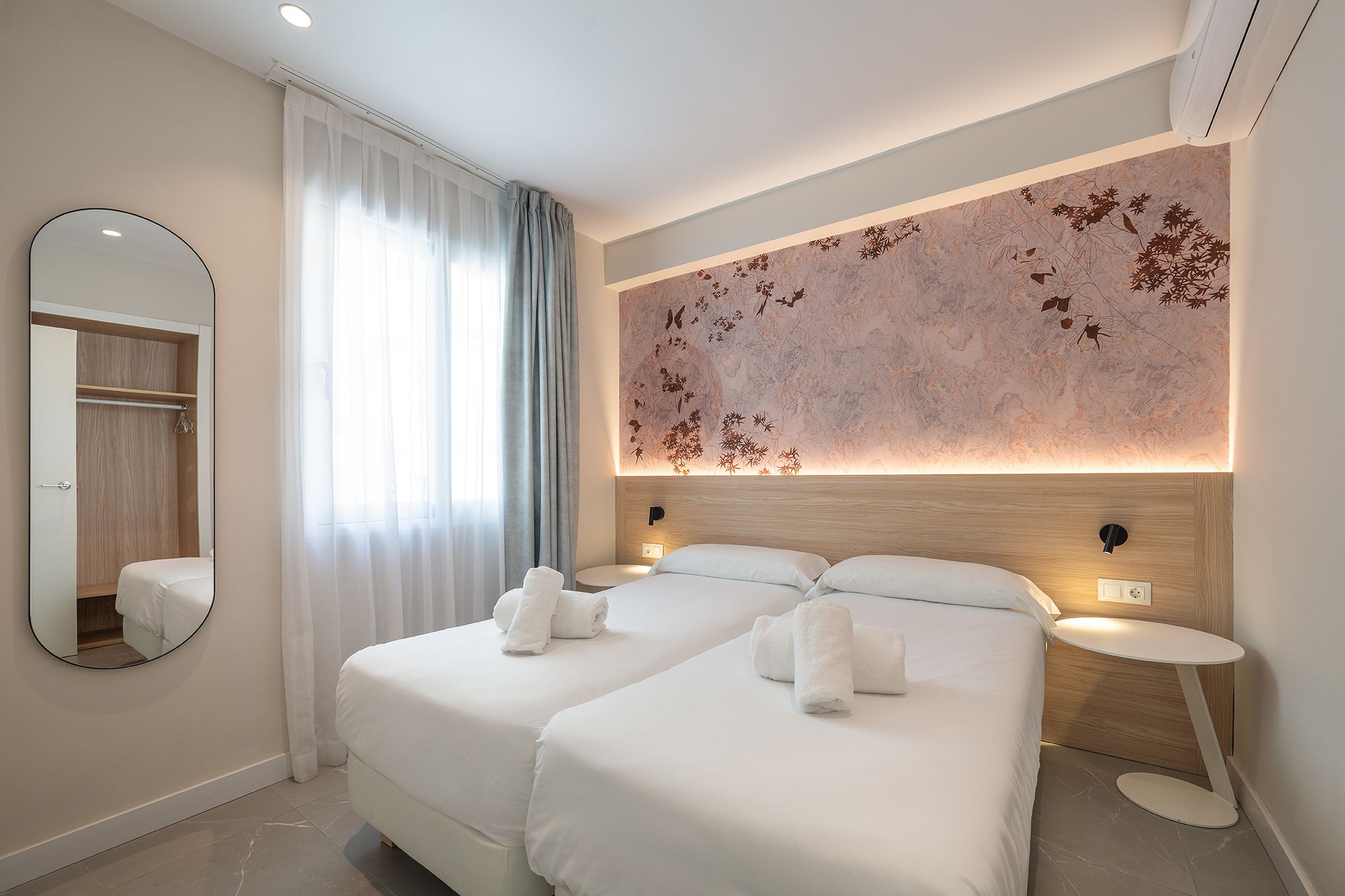 Stylish bedroom showcasing a white bed and wall mural. Two individual bed united to make a double bed for guests