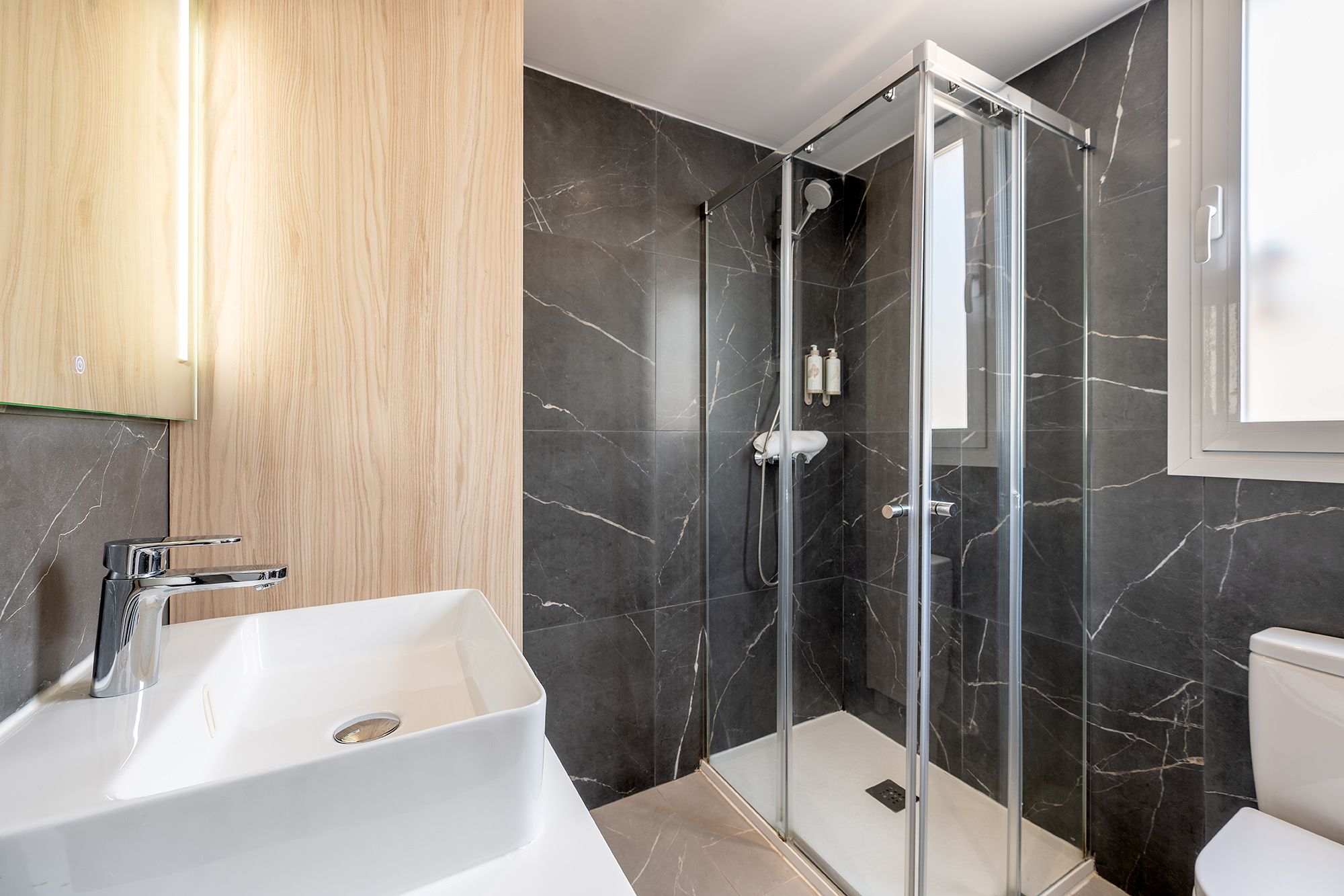 Elegant bathroom with a glass shower, a contemporary sink, soft towels, and free shampoo available for use.