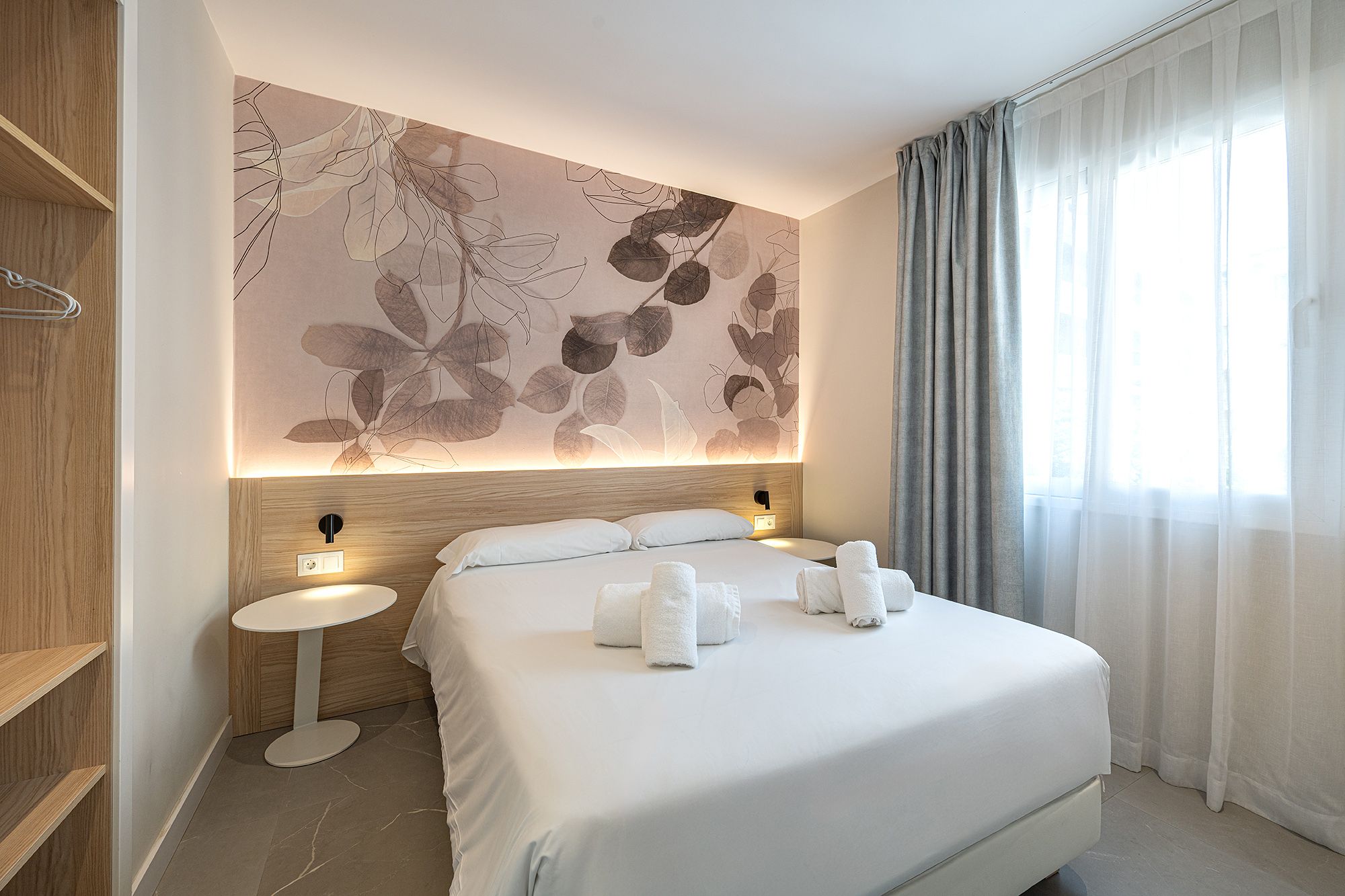Una elegante habitación de apartahotel con una cama bien hecha y un mural artístico en la pared que realza el ambiente.