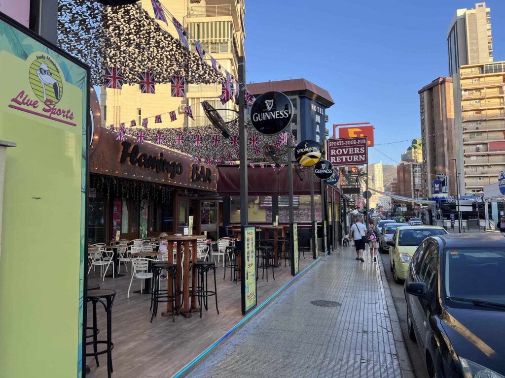 A street scene on Calle Gerona, Benidorm, with a restaurant and a car parked nearby.
