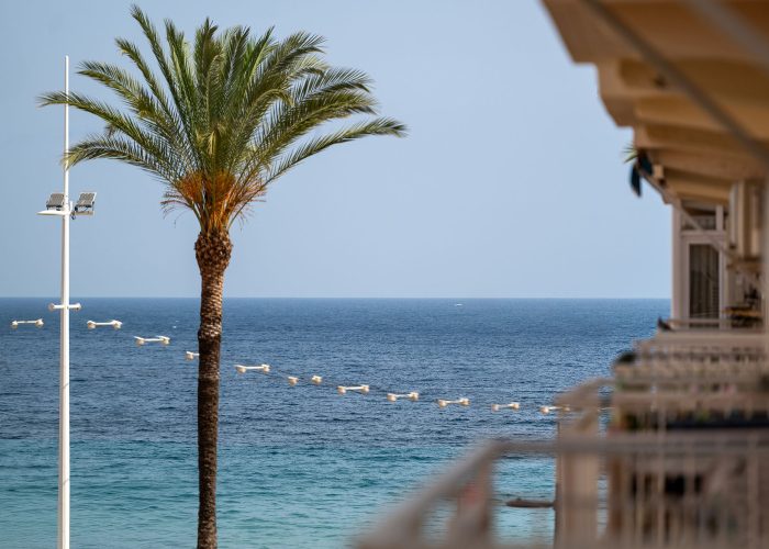 Ocean view from a balcony overlooking Benidorm beach, featuring sandy shores and gentle waves.