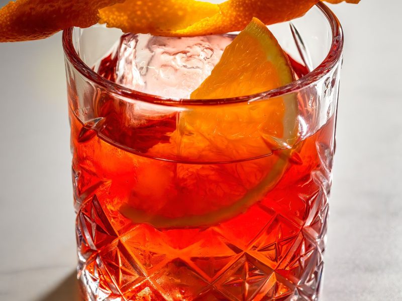 A refreshing beverage in a glass, elegantly topped with a slice of orange peel.