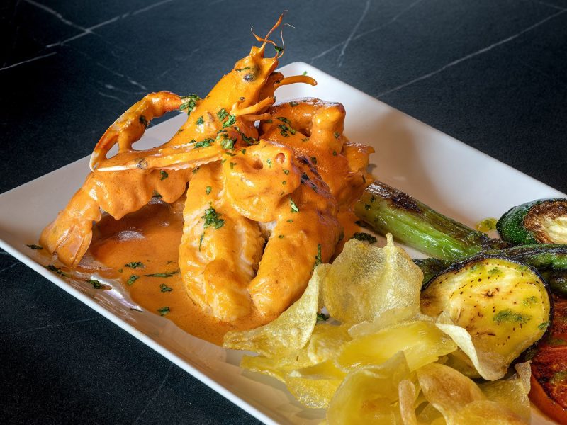 A colorful plate featuring shrimp, fresh vegetables, and crispy chips, arranged appetizingly for a delightful meal.