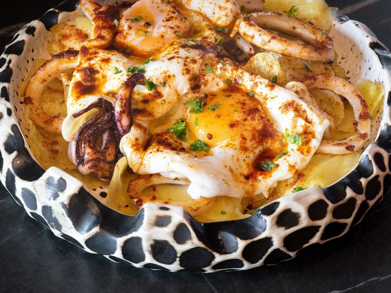 A steaming bowl of mixed food, elegantly topped with a runny egg, creating a delightful and satisfying dish.
