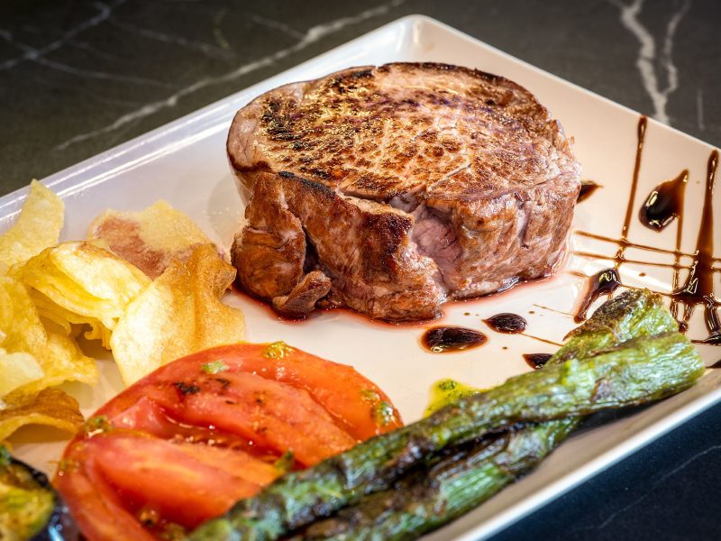 A gourmet plate with a succulent steak, fresh asparagus spears, and fluffy roasted potatoes.