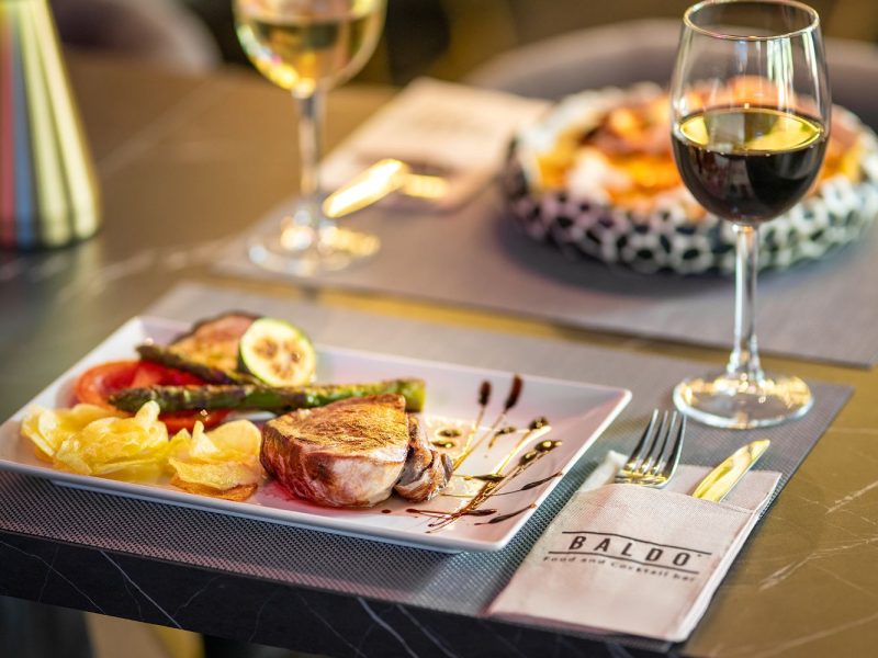 A beautifully set table featuring two plates of gourmet food and a bottle of wine, ready for a delightful meal.