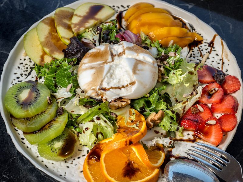 A colorful plate filled with fresh fruit and vegetables, accompanied by a shiny fork resting on the side.