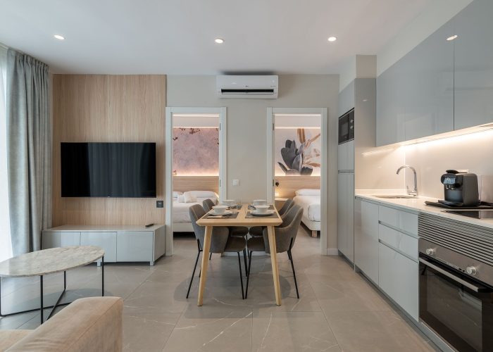 Contemporary apartment showcasing a kitchen, dining area, two bedrooms, smart TV, and air conditioning.