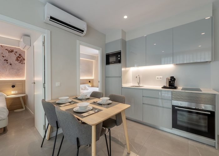 A stylish small kitchen and dining area in a modern apartment, highlighting efficient use of space and modern furnishings.