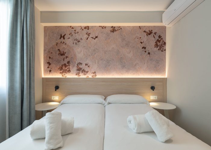 Cozy bedroom featuring a white bed, wall mural and bright window