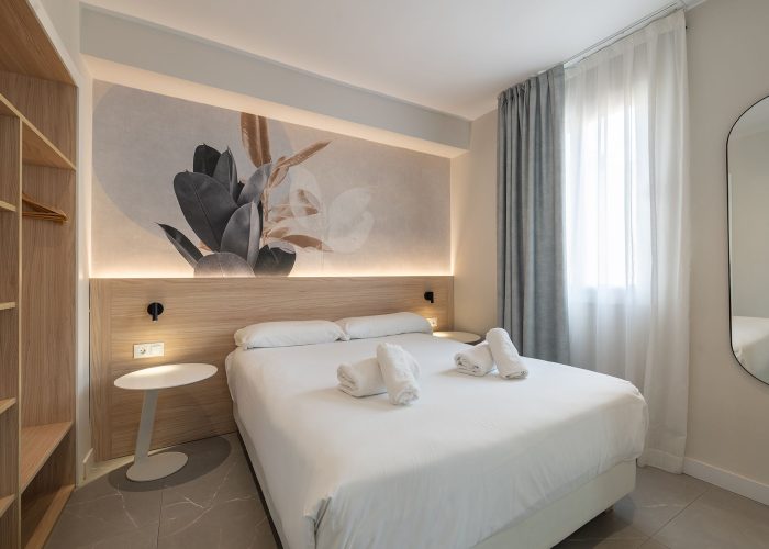 A well-decorated apartment room showcasing a bed and a vibrant wall painting.