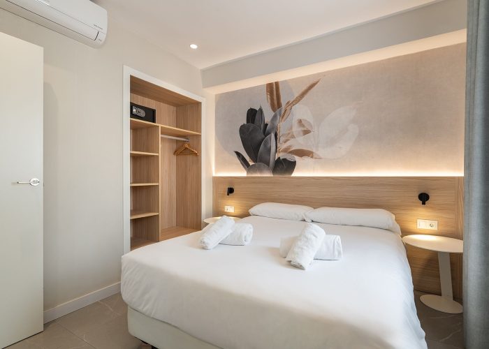 Inviting bedroom with a white bed, decorative wall mural, air conditioning, and free towels, all in a secure environment.