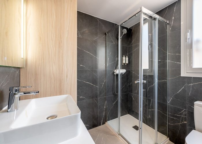 Elegant bathroom with a glass shower, a contemporary sink, soft towels, and free shampoo available for use.