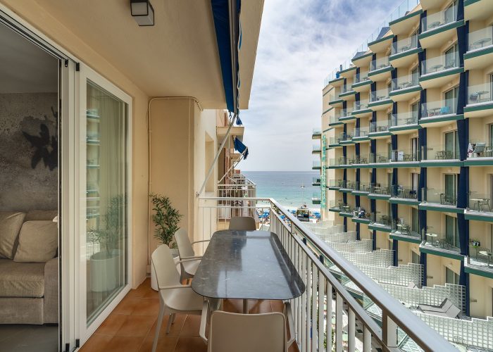 A serene balcony with a table and chairs, providing a picturesque view of the ocean horizon.