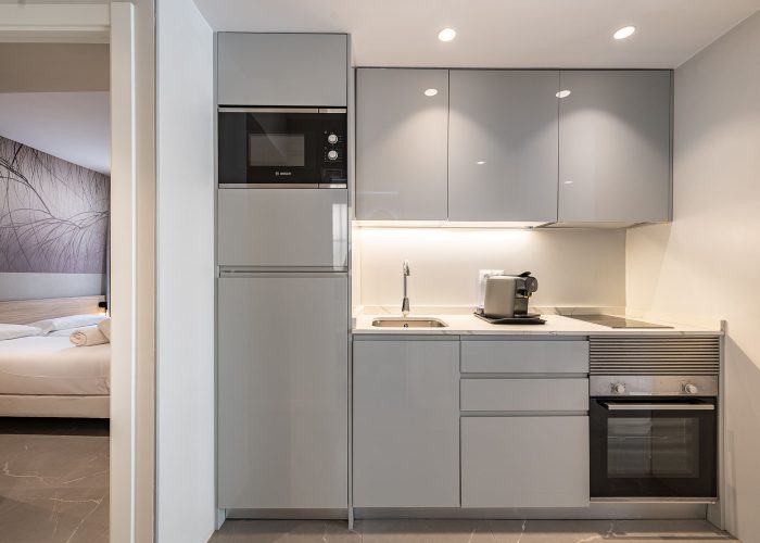 A compact kitchen with essential appliances: a sink, microwave, and oven, coffee machines, designed for efficient cooking.