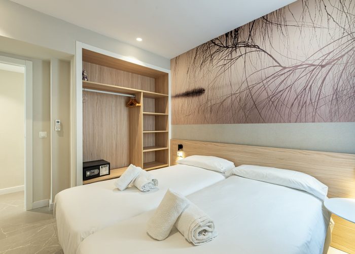 A cozy bedroom featuring two beds and a colorful painting on the wall, creating a welcoming atmosphere for tourist stays at Benidorm