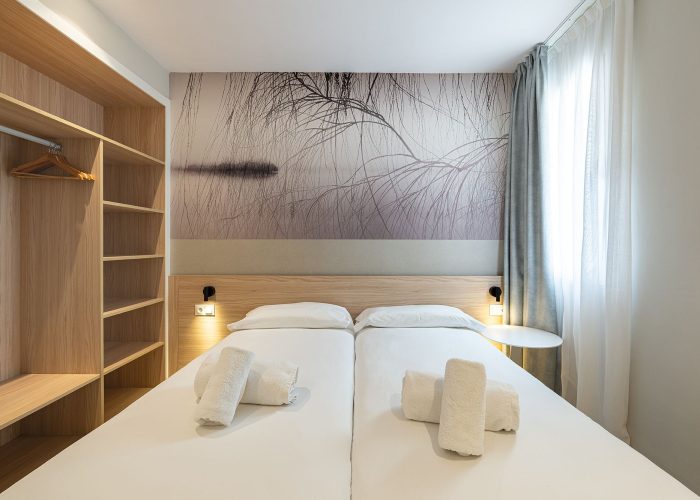 A cozy bedroom featuring two beds and a colorful painting on the wall, creating a welcoming atmosphere.