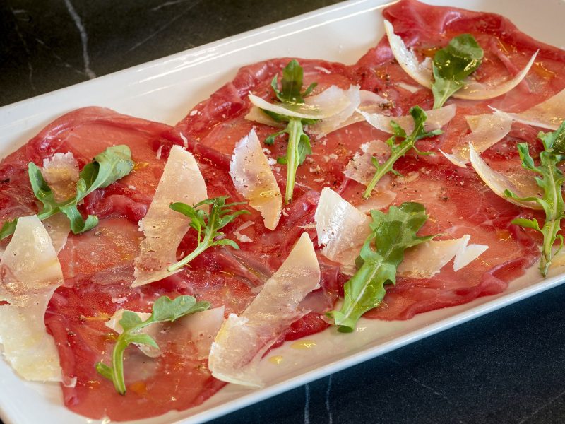 Un colorido plato de carne a la parrilla y verduras frescas dispuestas bellamente sobre una mesa de madera.