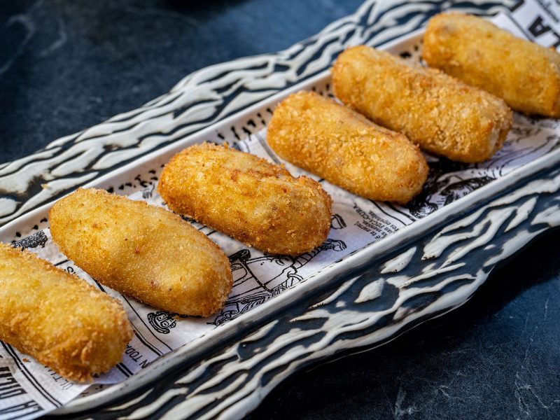 Un plato lleno de frituras crujientes, como pollo dorado, patatas fritas y aros de cebolla.