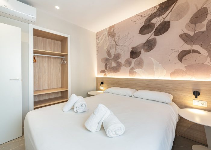 A charming aparthotel room featuring a comfortable double bed and a decorative wall mural that adds a personal touch with minimalistic style