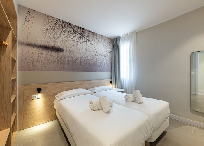 A spacious bedroom showcasing two beds and a vibrant wall painting, perfect for a comfortable stay at Benidorm