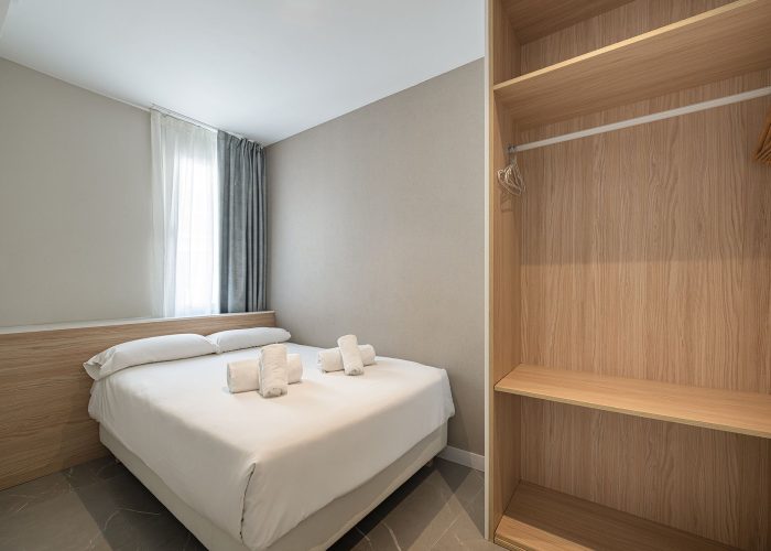 A compact bedroom with a single bed and a closet, creating a simple and functional space.